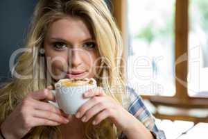Beautiful young woman having coffee in cafe