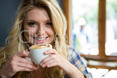 Smiling young woman having coffee in cafe