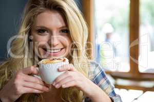 Smiling young woman having coffee in cafe