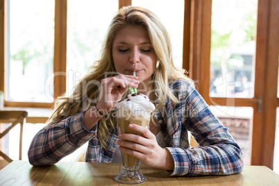 Woman drinking milkshake with straw in cafe
