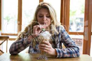 Woman drinking milkshake with straw in cafe