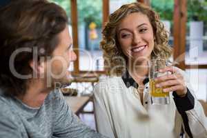 Woman having juice while looking at man in coffee shop