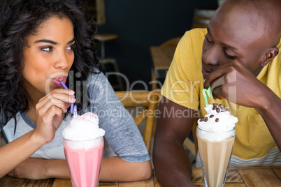 Loving couple having milkshakes at table in coffee shop