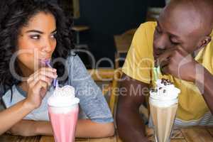 Loving couple having milkshakes at table in coffee shop