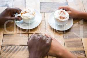 Couple having coffee while holding hands in cafe
