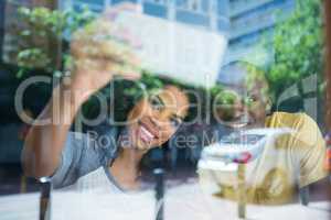 Couple taking selfie in coffee shop seen through window