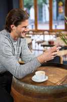 Man using smart phone at table in coffee shop