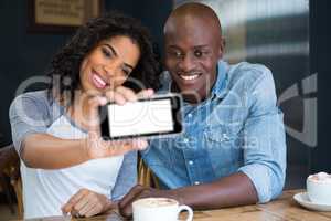 Couple taking selfie with smart phone in coffee shop