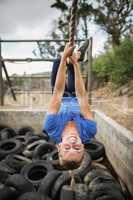 Woman climbing rope during obstacle course training