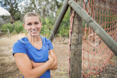 Fit woman standing with arms crossed during boot camp training