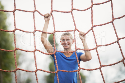 Woman climbing a net during obstacle course