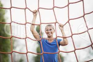 Woman climbing a net during obstacle course