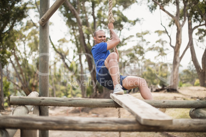 Fit man climbing a rope during obstacle course