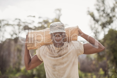 Military soldier carrying a tree log during obstacle course