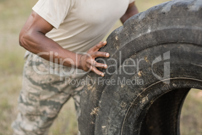 Mid section of military soldiers exercising with tyre