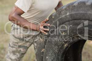 Mid section of military soldiers exercising with tyre