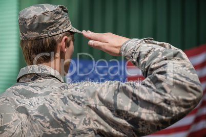 Rear view of military soldier giving salute to american flag