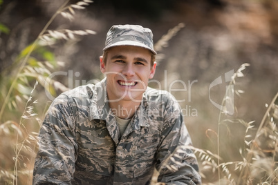 Portrait of happy military soldier crouching in grass