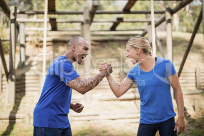 Fit man and woman greeting each other during obstacle course