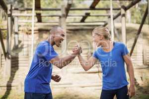 Fit man and woman greeting each other during obstacle course
