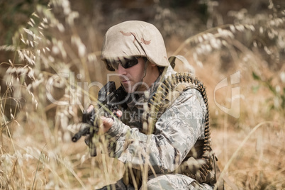 Military soldier hiding in grass while guarding with a rifle