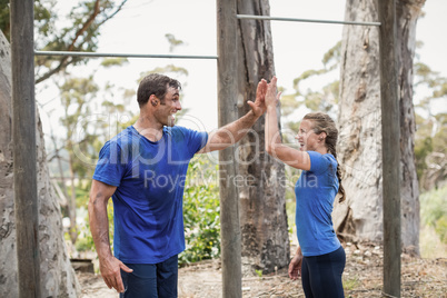 Smiling man and woman giving high five during obstacle course