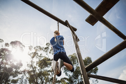 Fit woman climbing down the rope during obstacle course