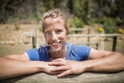 Smiling woman leaning on a hurdle during obstacle course