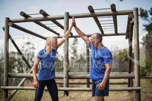 Fit woman and man giving a high five to each other during obstacle course