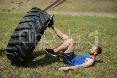 Fit man performing leg workout with tier during obstacle course
