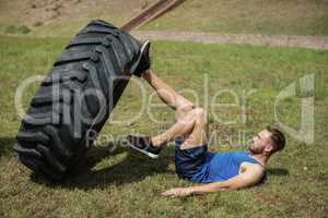 Fit man performing leg workout with tier during obstacle course