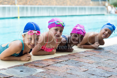 Happy little swimmers leaning at poolside