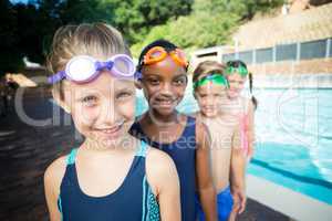 Smiling little swimmers standing at poolside