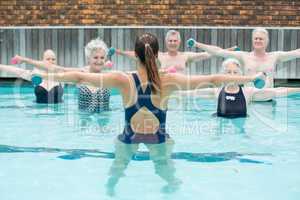 Instructor with senior swimmers exercising in swimming pool