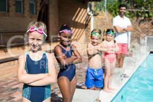 Confident little swimmers with male instructor at poolside