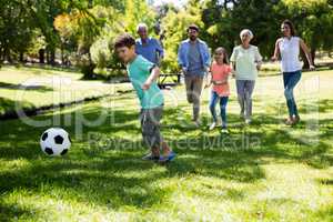 Multi generation family playing football in park