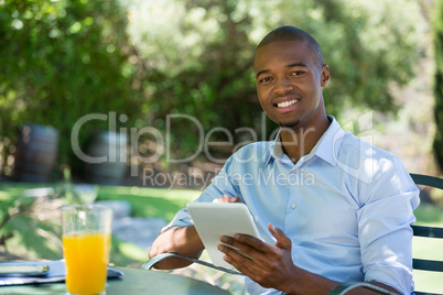 Smiling businessman using digital tablet at outdoor restaurant