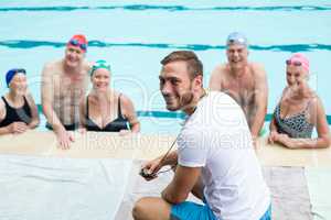 Cheerful male instructor assisting senior swimmers