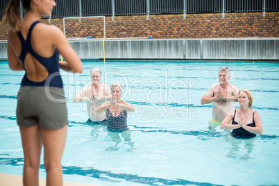 Mid section of yoga trainer assisting senior swimmers