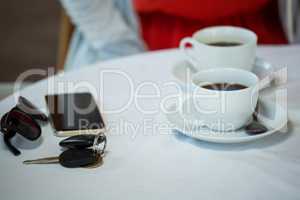 Coffee cups and personal accessories on cafe table