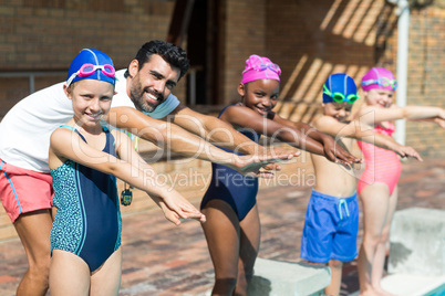 Male instructor and children preparing for jumping in swimming pool