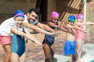 Male instructor and children preparing for jumping in swimming pool