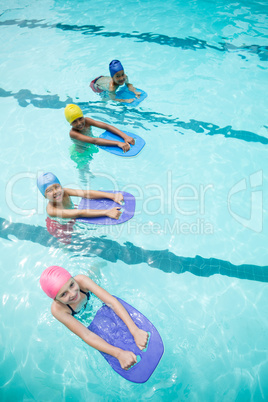 Children using kickboard while swimming in pool