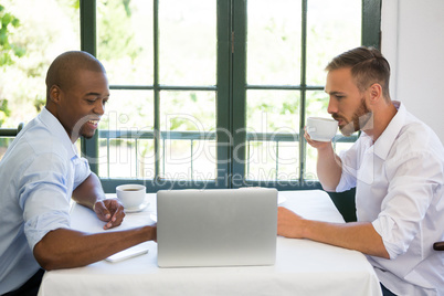 Business people discussing over laptop in restaurant