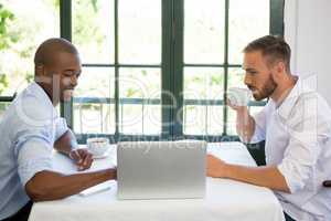 Business people discussing over laptop in restaurant