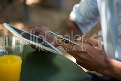 Man holding mobile phone and digital tablet at restaurant