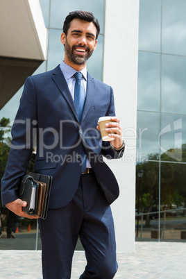 Portrait of businessman holding disposable cup and diary