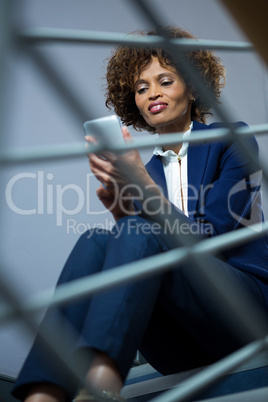 Businesswoman using mobile phone while sitting on steps