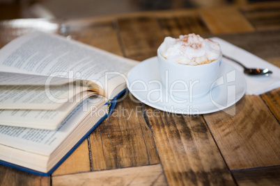 Coffee cup by open book on table in cafeteria