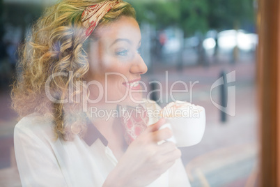 Woman drinking coffee in cafeteria seen through window